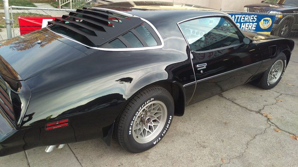 A black car is parked in front of a sign that says batteries here.