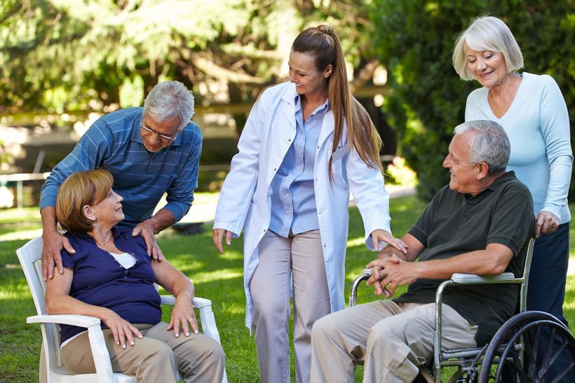 A group of people are standing around a man in a wheelchair.