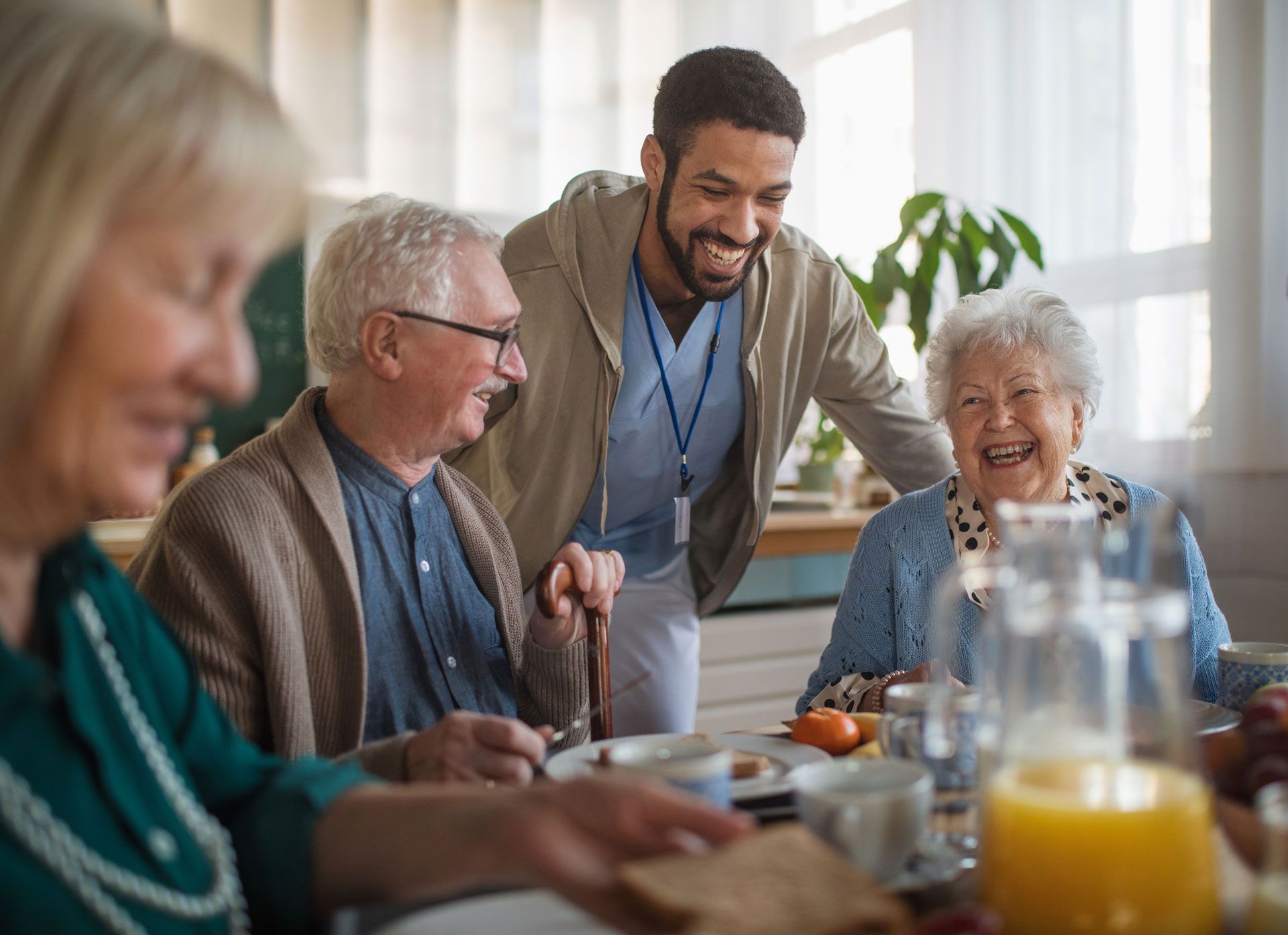 A man is standing next to a group of elderly people sitting at a table.
