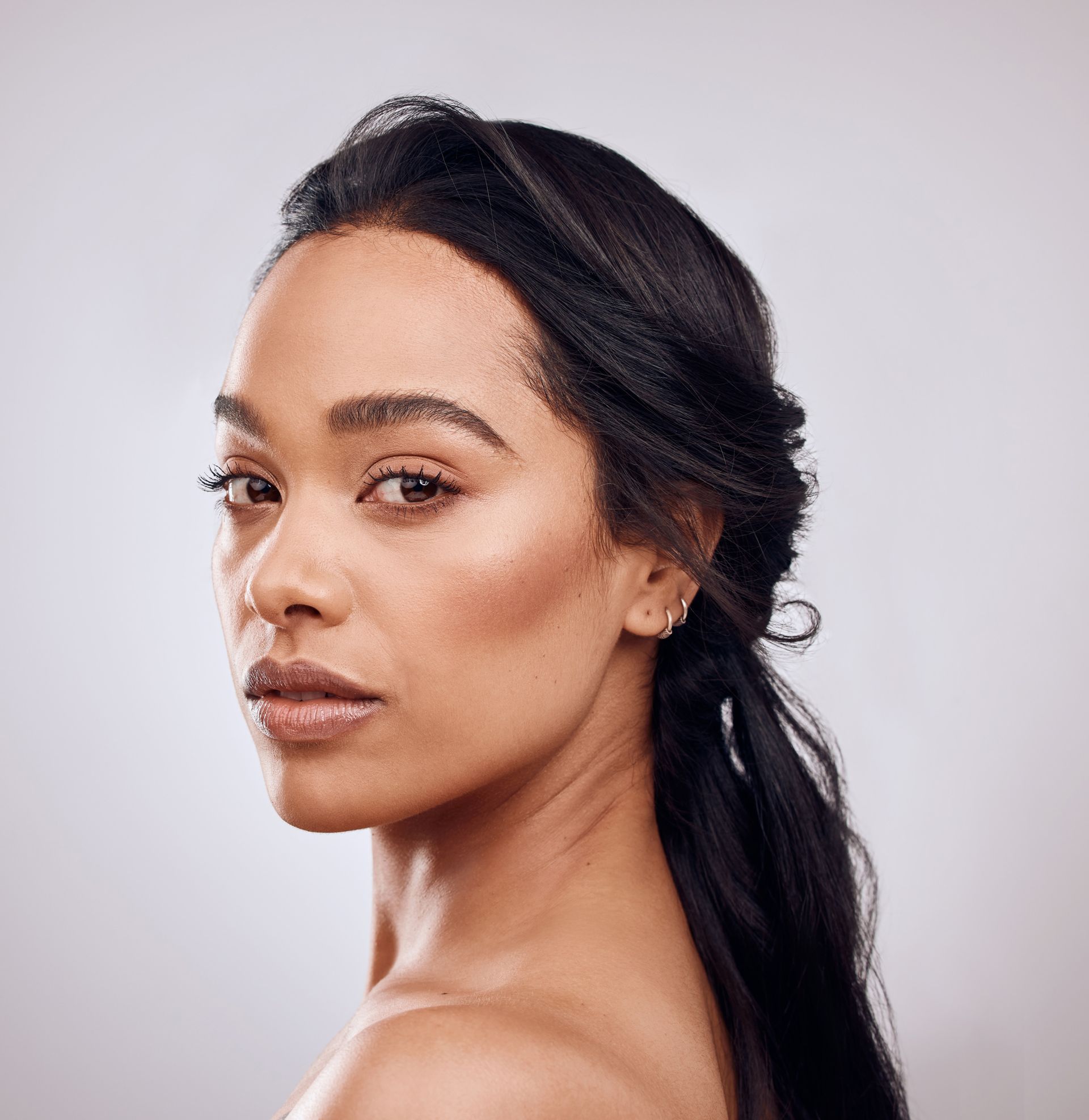 A close up of a woman 's face with her hair in a ponytail.