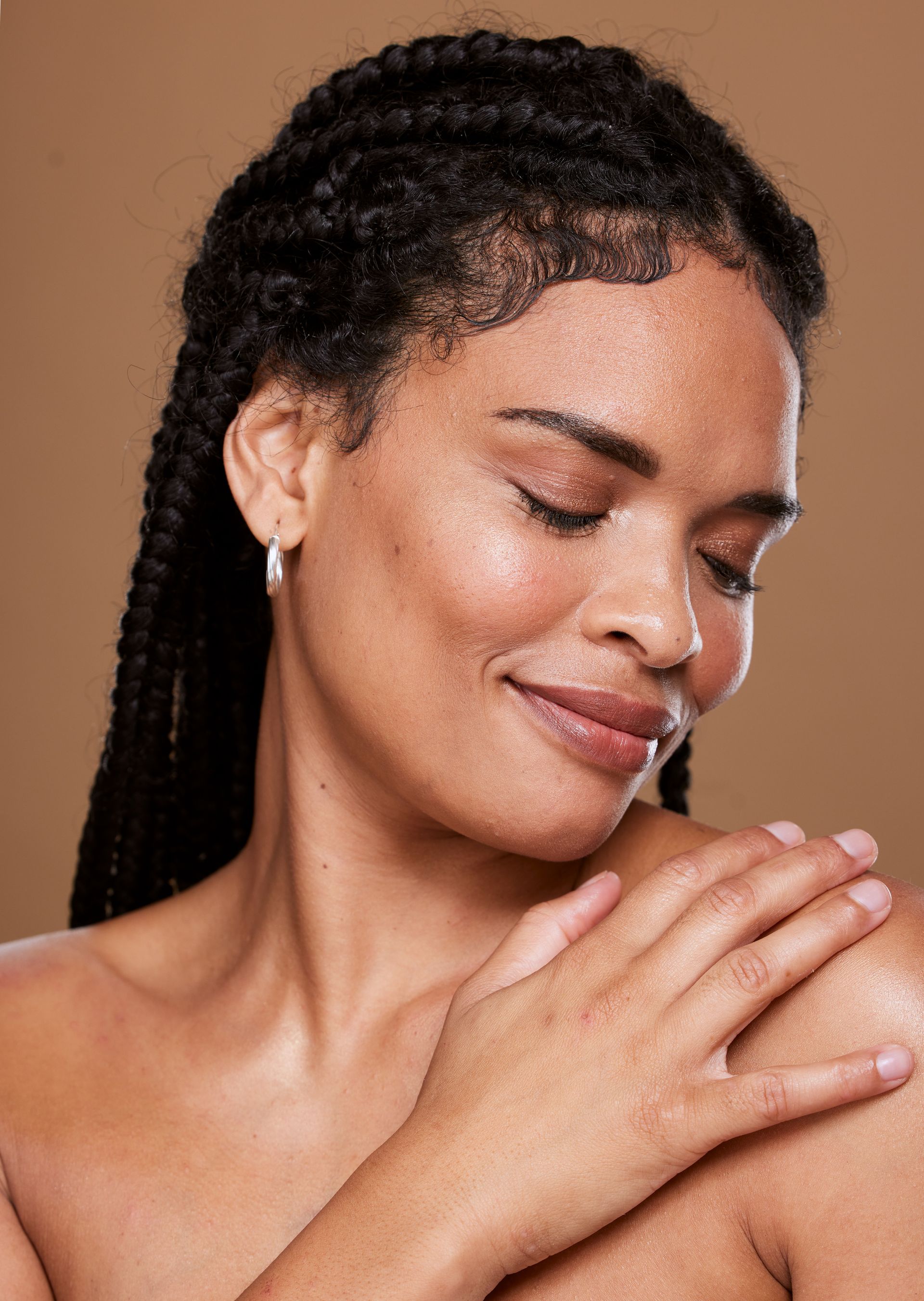 A woman is touching her shoulder with her hands and smiling.