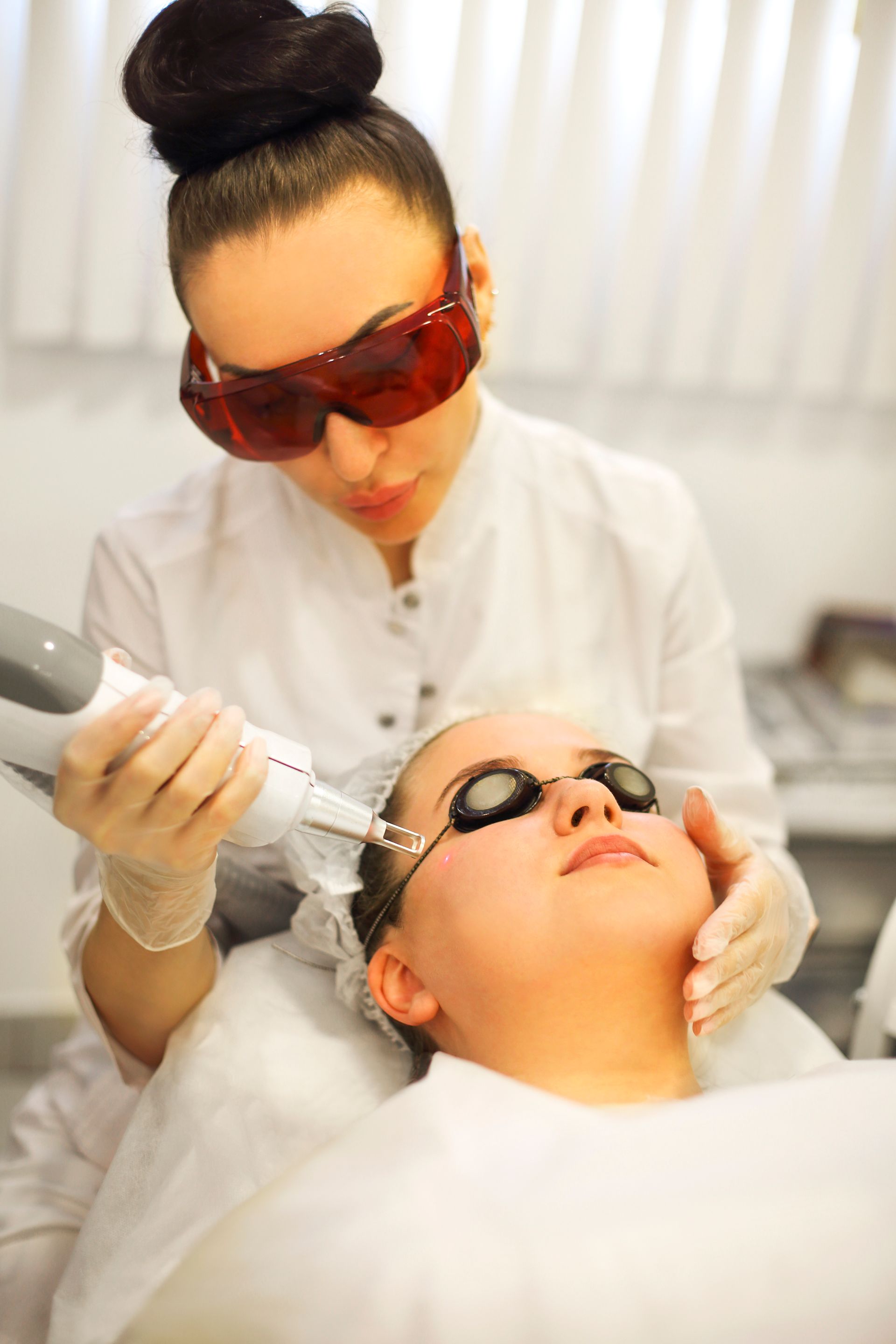 A woman is getting a laser treatment on her face.
