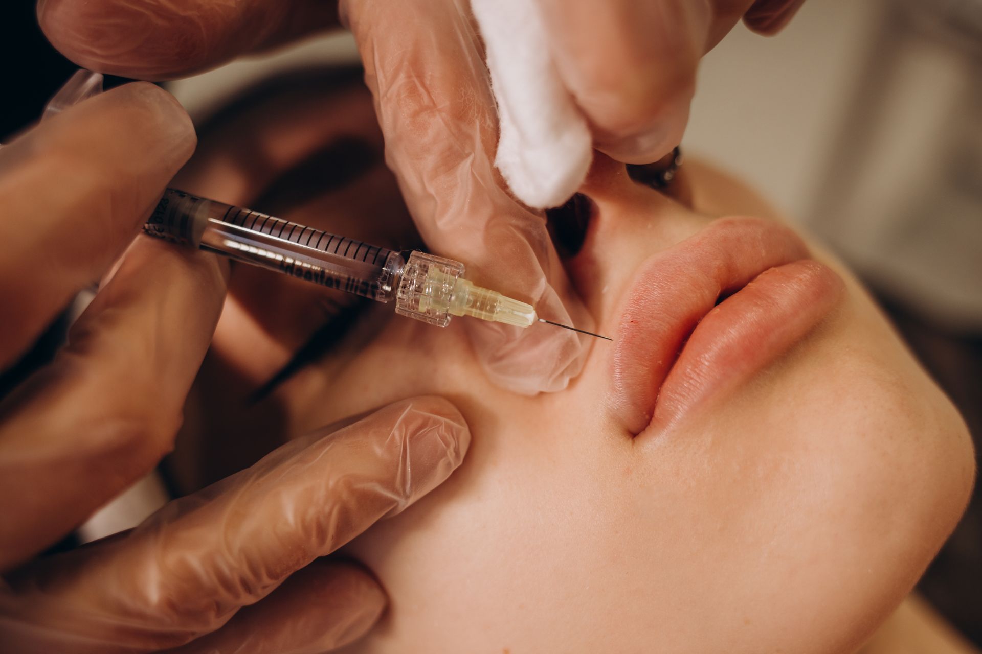 A woman is getting a botox injection in her lips.