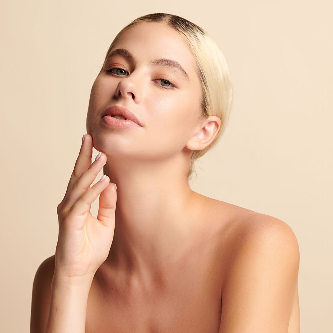 A woman is touching her face with her hand and looking at the camera.