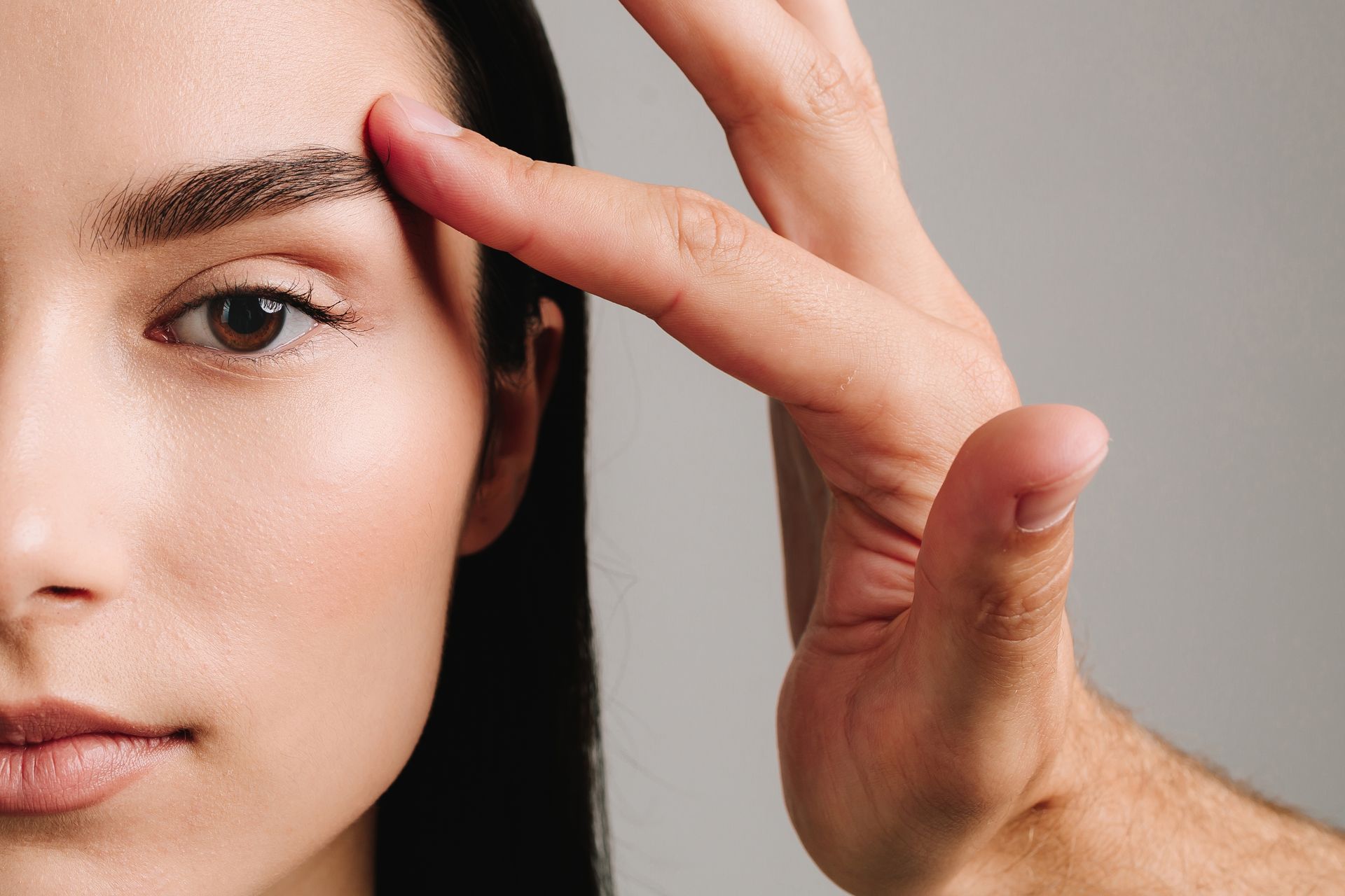 A man is touching a woman 's eyebrow with his finger.