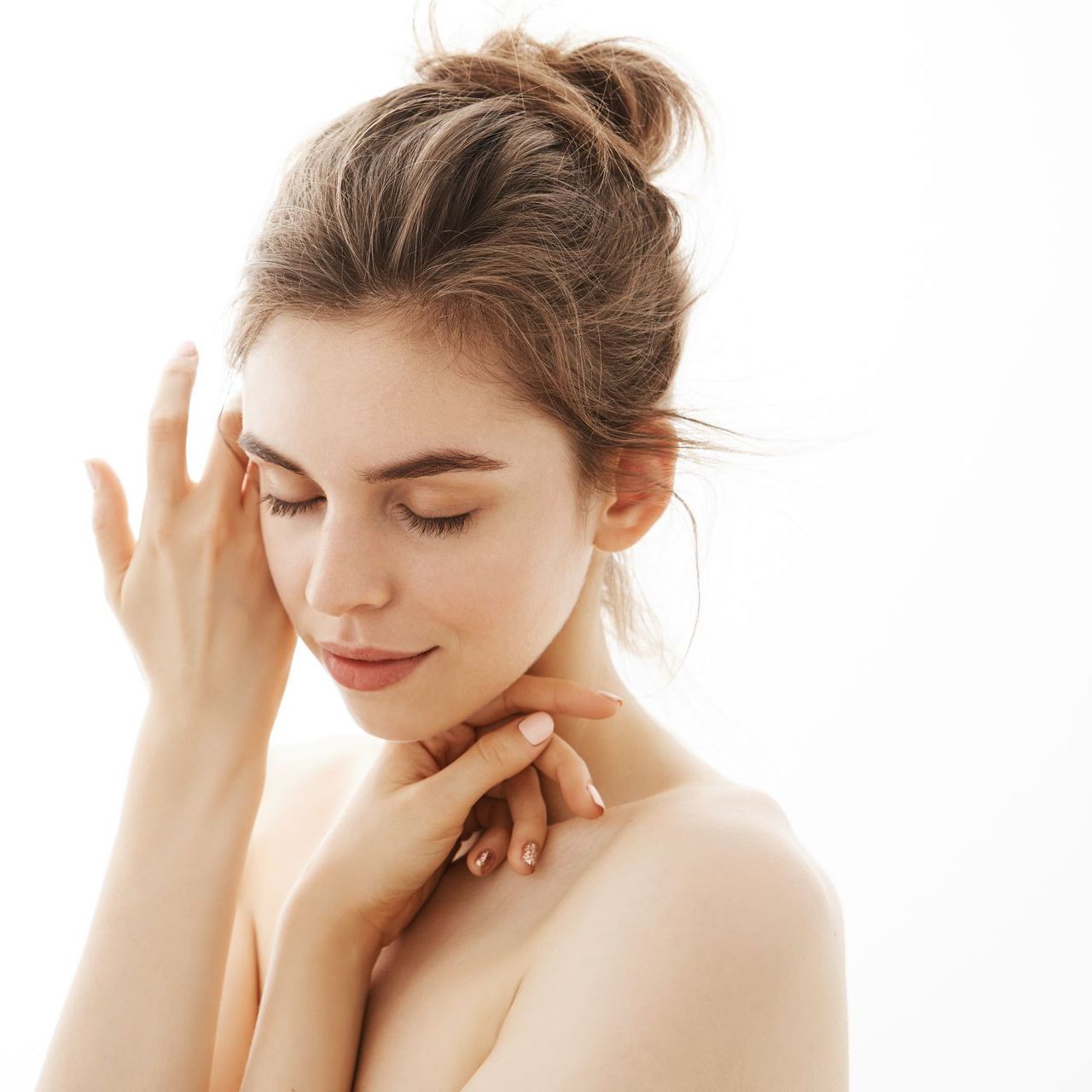 A woman is touching her face with her hands and smiling.