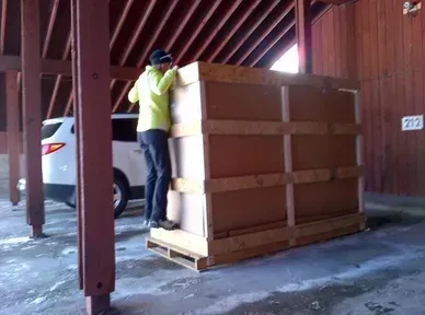 A man is standing on a wooden crate in a barn