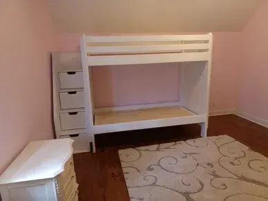 A bedroom with a bunk bed , dresser , and rug.