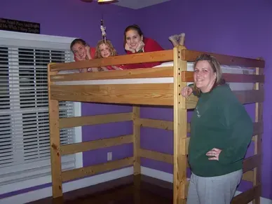 A group of people are standing under a bunk bed