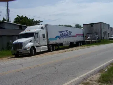 A white semi truck is parked on the side of the road.