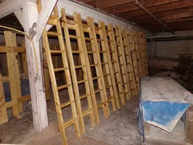A bunch of wooden ladders are lined up in a room.