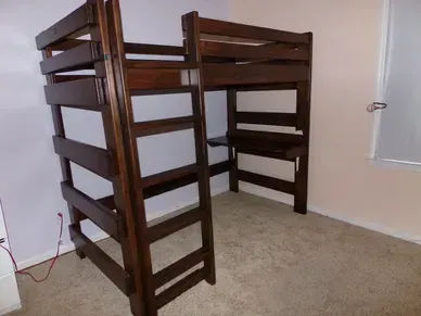 A wooden bunk bed with a desk underneath it