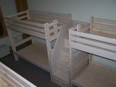 Three bunk beds with stairs in a room.