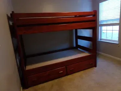 A wooden bunk bed is sitting in a bedroom next to a window.