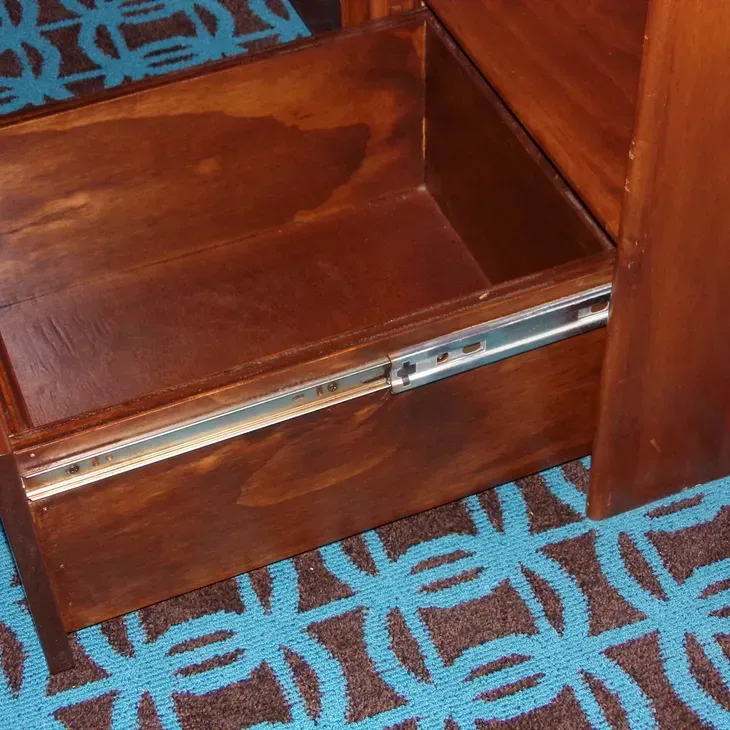 A wooden drawer with a blue carpet underneath it