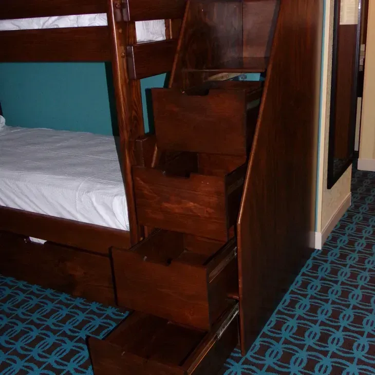 A bunk bed with stairs and drawers underneath it