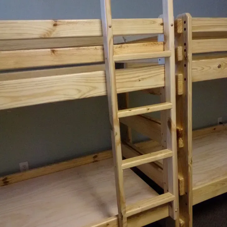 A wooden bunk bed with a ladder attached to it