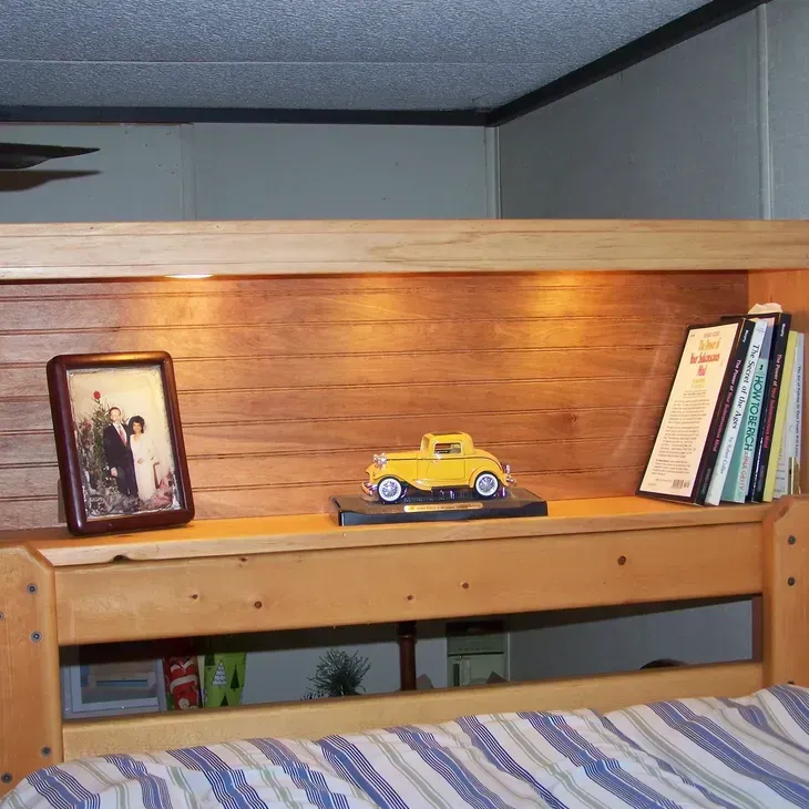A picture of a bride and groom sits on a wooden shelf above a bed