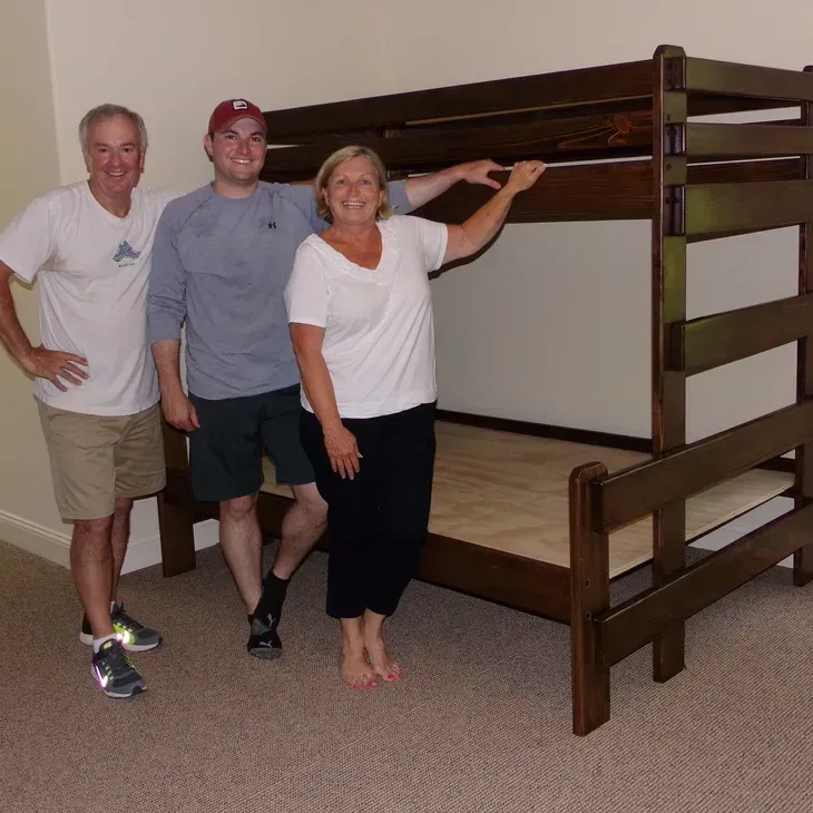 Three people standing in front of a bunk bed