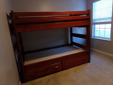 A bunk bed is sitting in a small room next to a window.