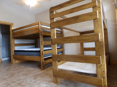 Two wooden bunk beds are in a bedroom next to each other.