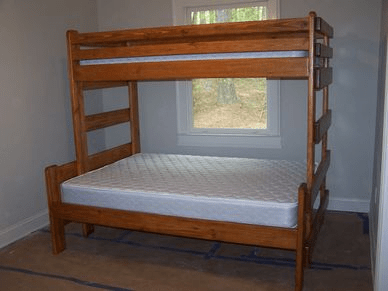 A bunk bed with a mattress in a room with a window.