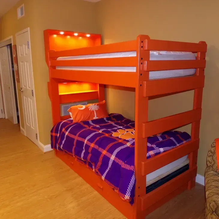 An orange bunk bed with a purple and orange plaid blanket