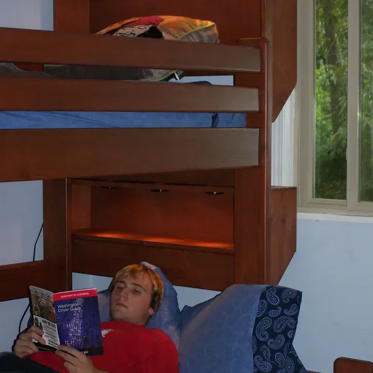 A person laying on a bunk bed reading a book