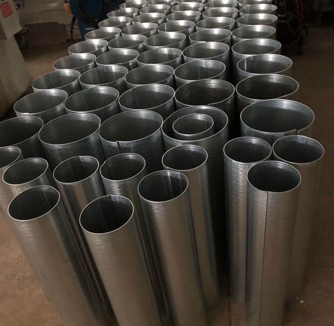 A stack of blue metal sheets on a conveyor belt in a factory.