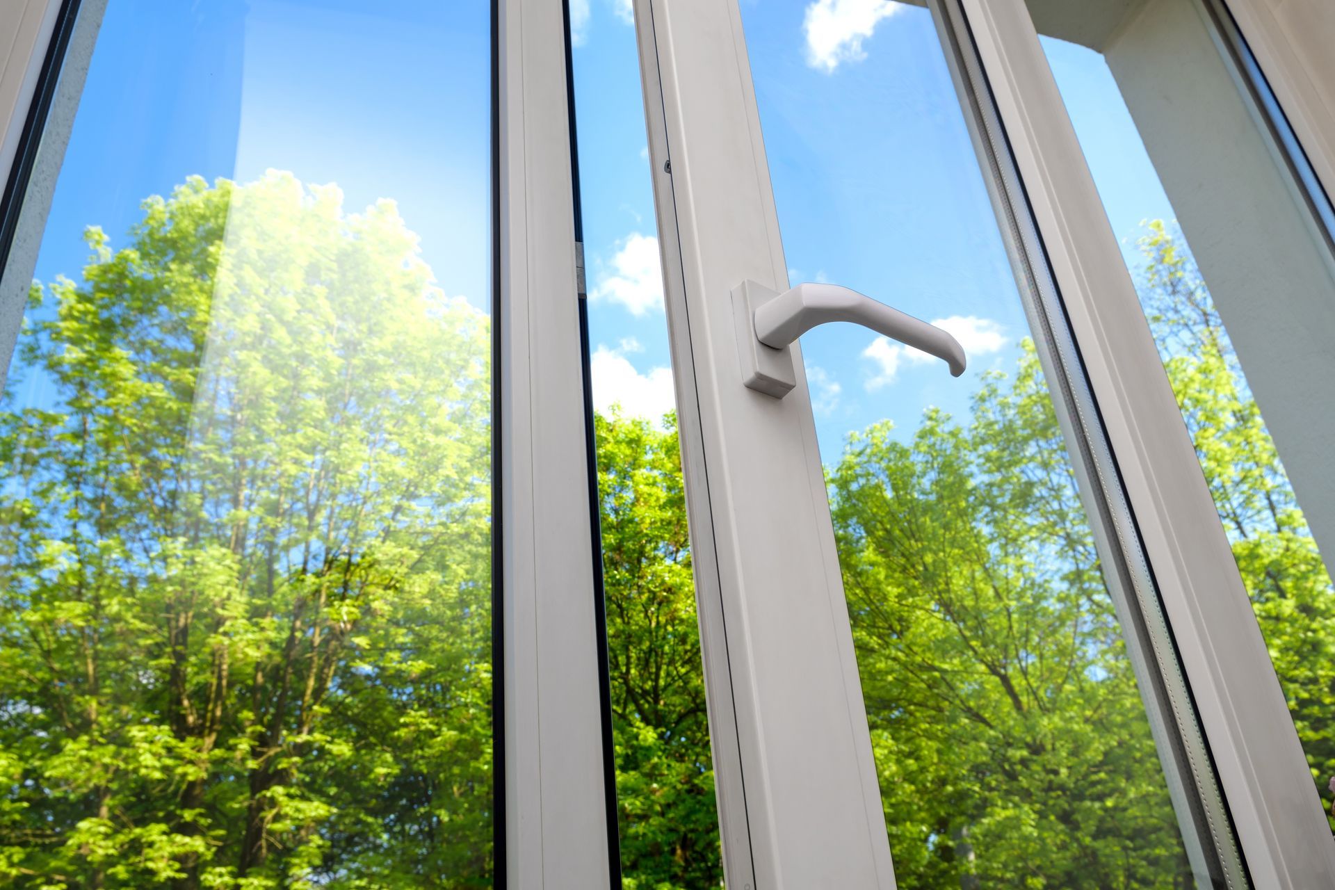 A close up of an open window with trees in the background.