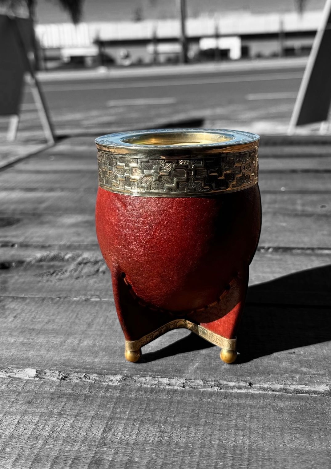 Una taza roja y dorada está sobre una mesa de madera.