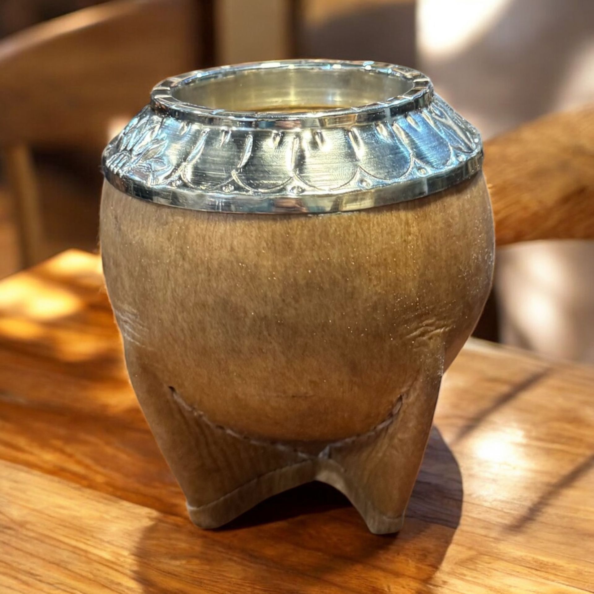 Un pequeño jarrón de madera está sobre una mesa de madera.