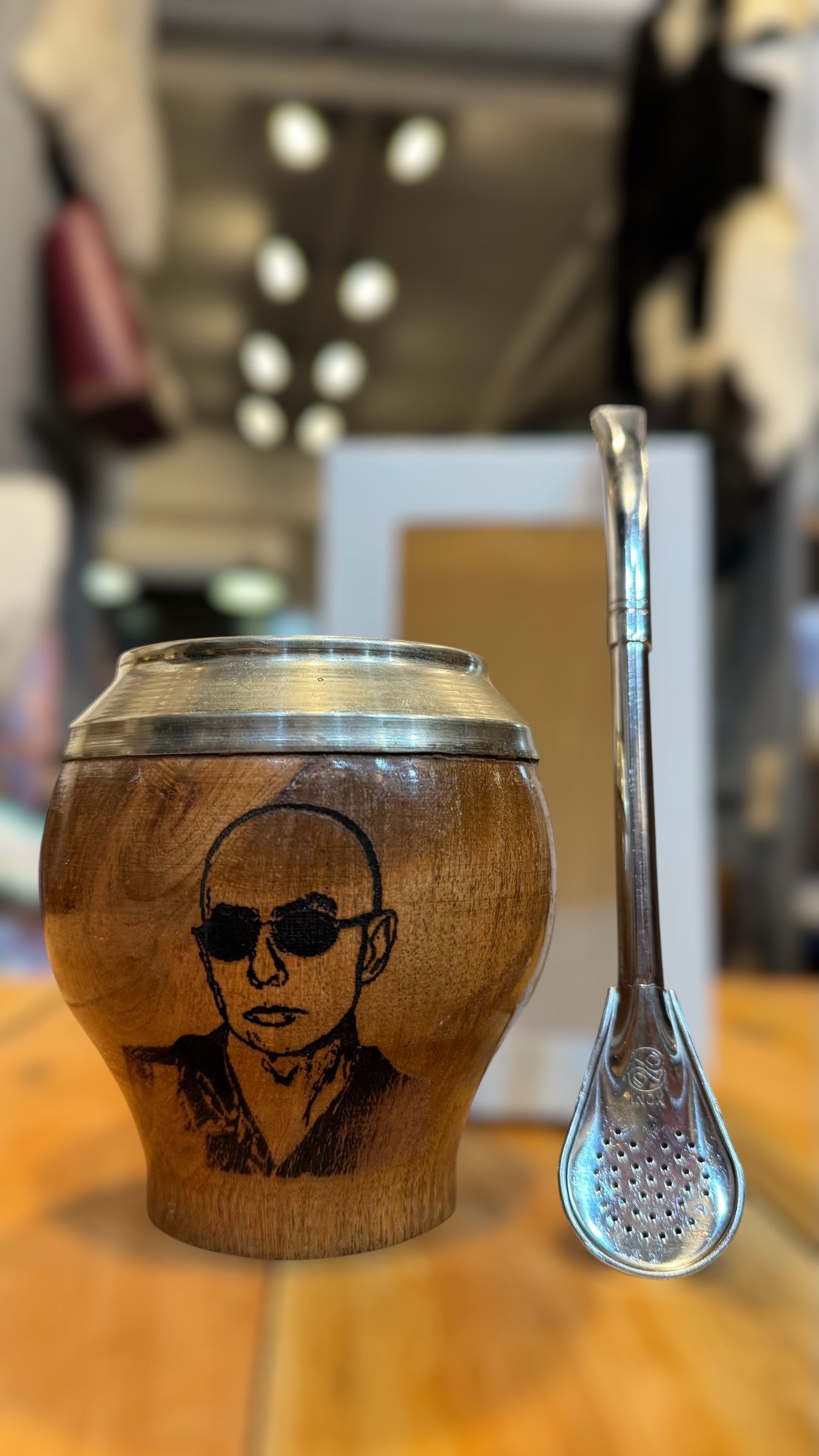 Una taza con la imagen de un hombre está sobre una mesa al lado de una cuchara.