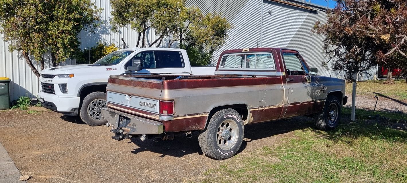 Two Trucks Parked Near a Building. One White, Modern Pickup Truck and An Older — Sparky's 4x4 Auto Electrical In Taminda, NSW