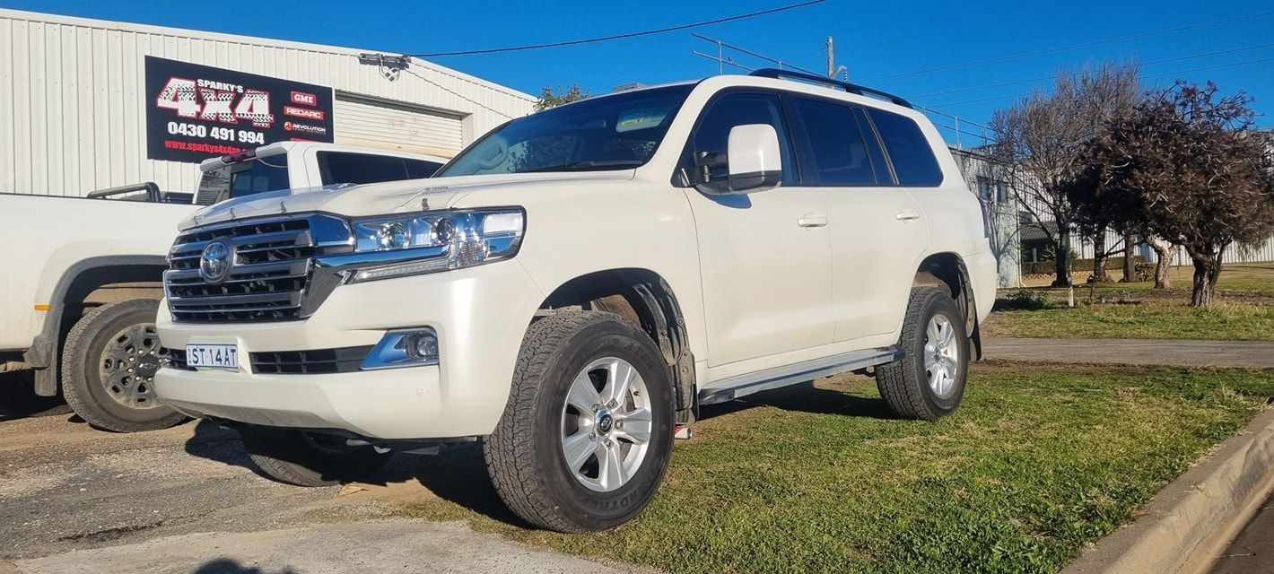 White Suv Parked on Grass Near a Building with 4x4 Sign — Sparky's 4x4 Auto Electrical In Armidale, NSW