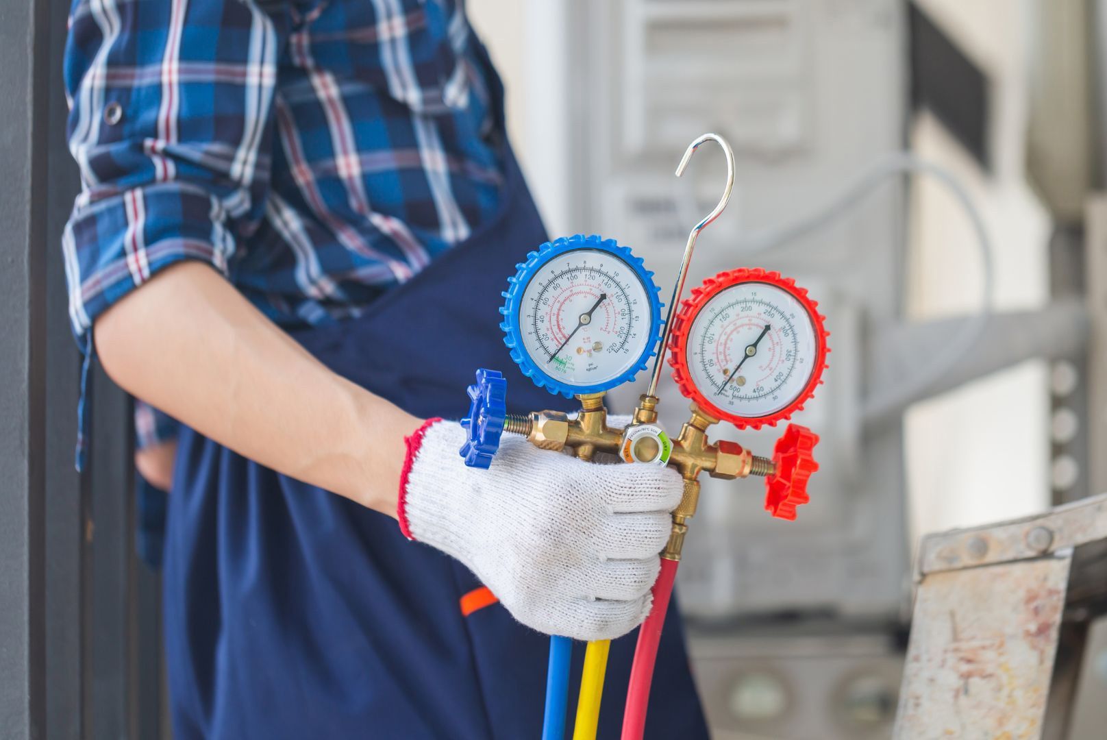 A man is holding a hose with two gauges attached to it.