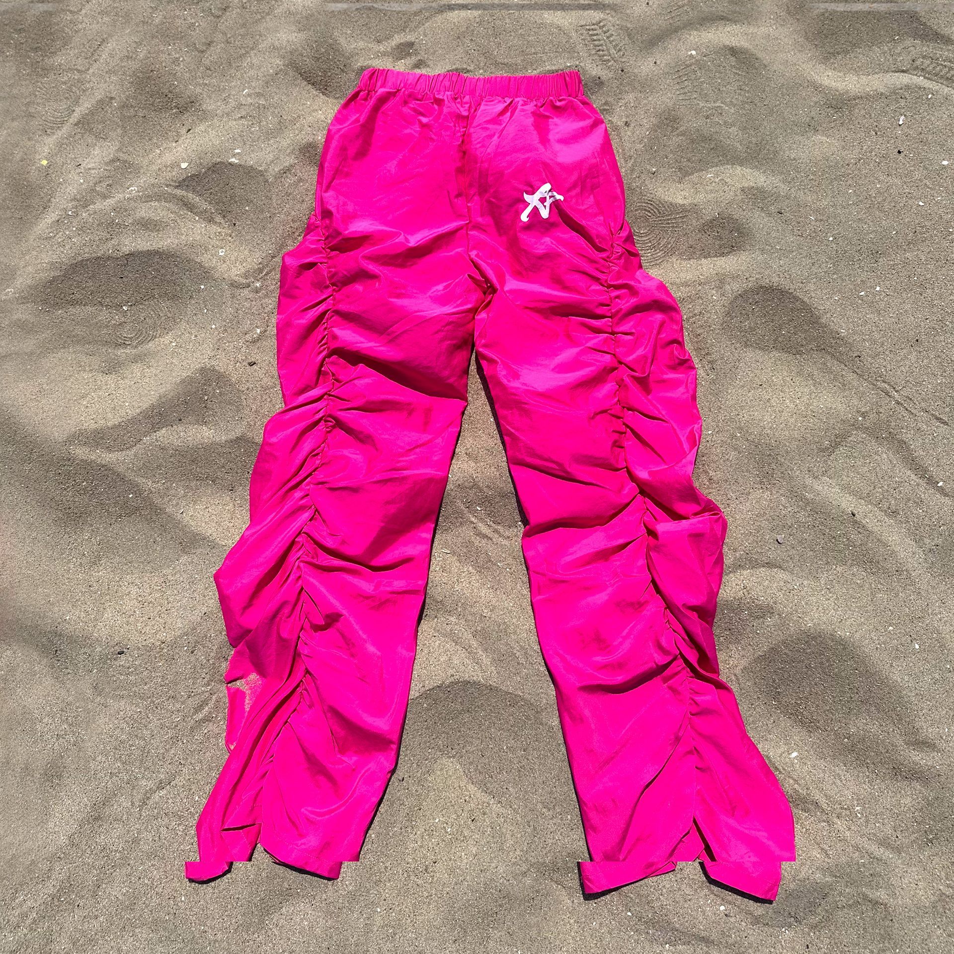 A pair of pink pants are laying on a sandy beach.