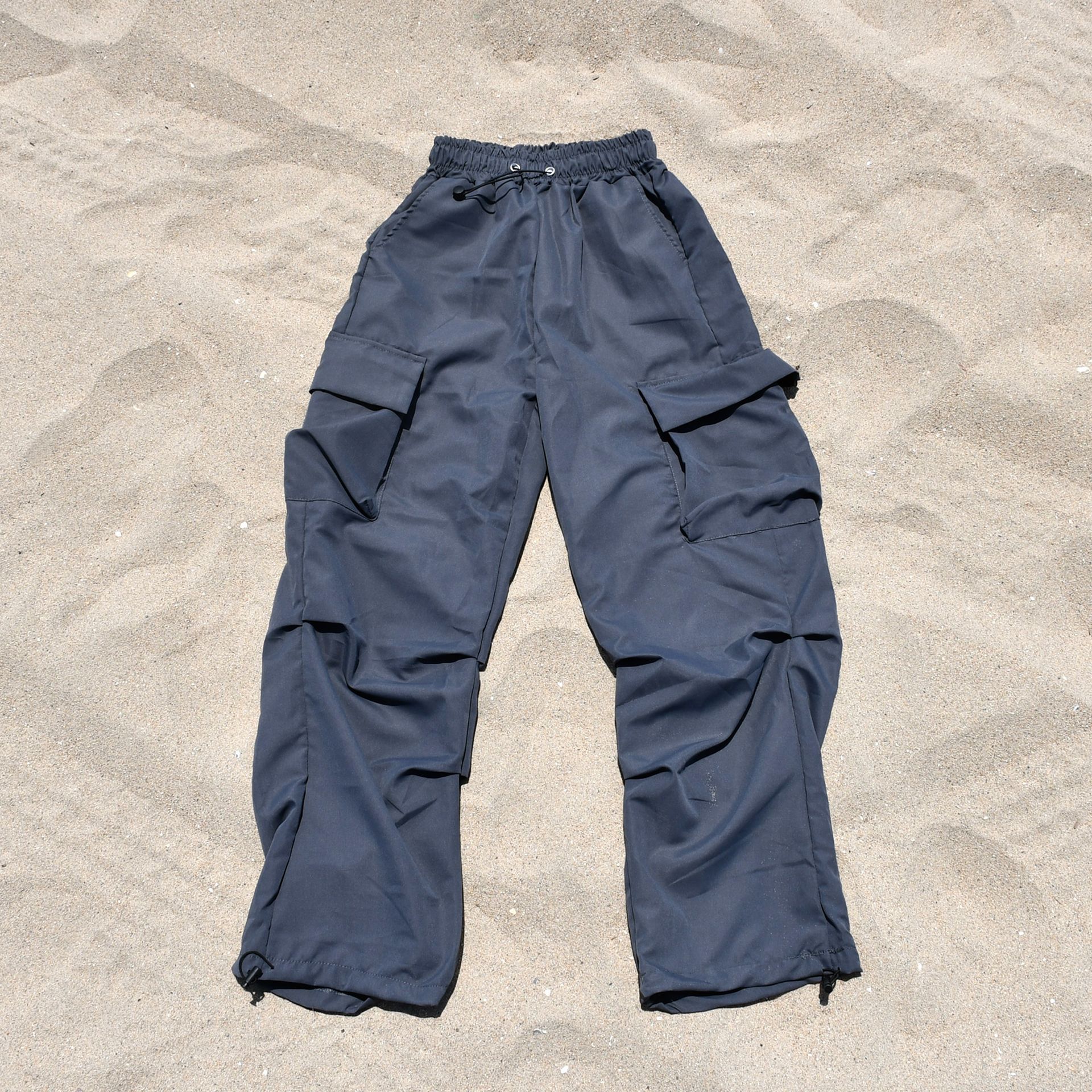 A pair of grey cargo pants laying on a sandy beach