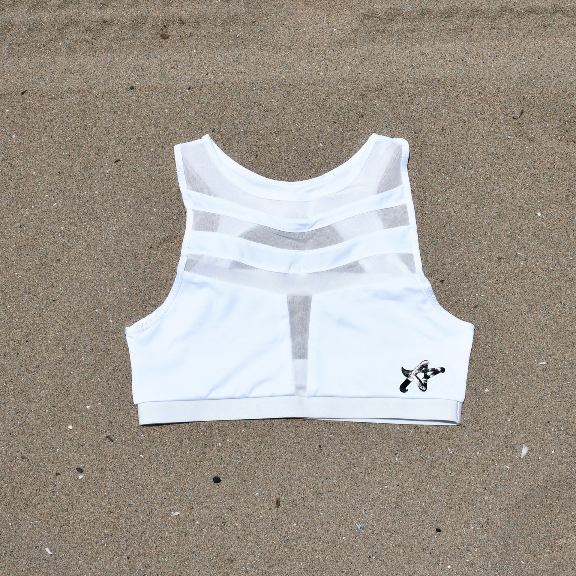 A white sports bra is laying on the sand