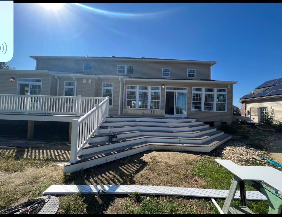 A large house with a large deck and stairs in the backyard.