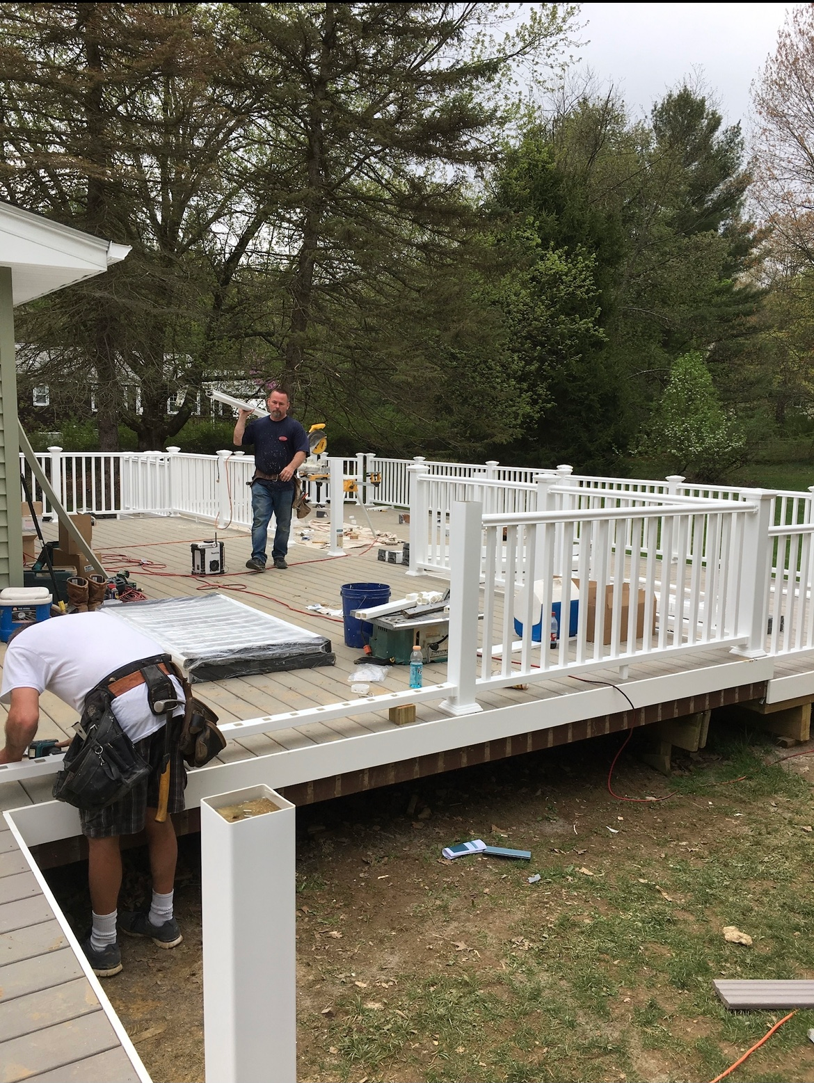 A man is working on a deck with a white railing.