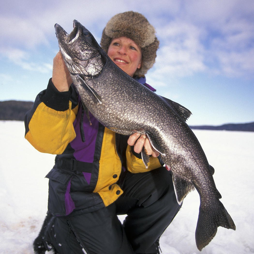 woman on frozen lake holding gigantic fish