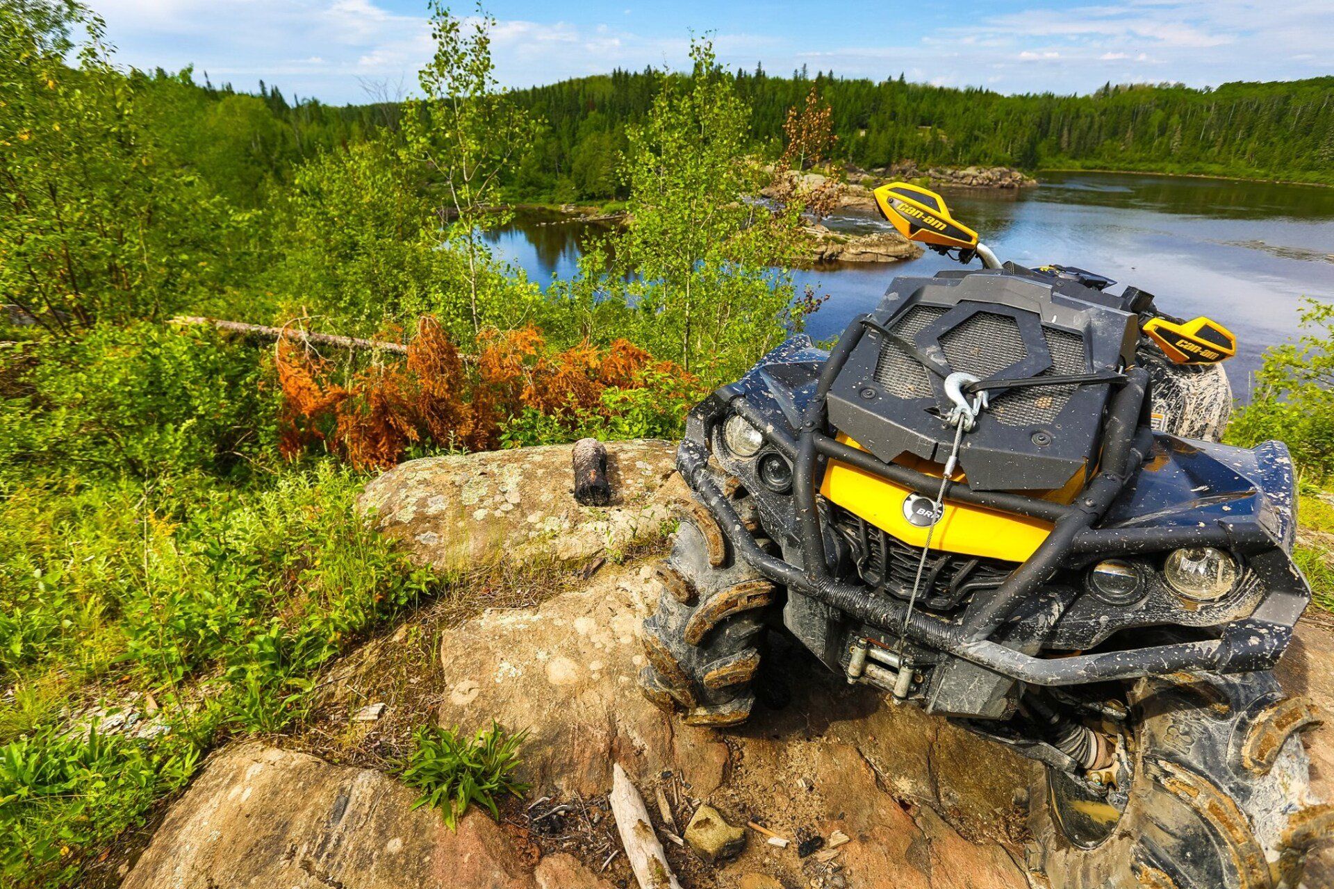 ATV on rock with river and forest in the background