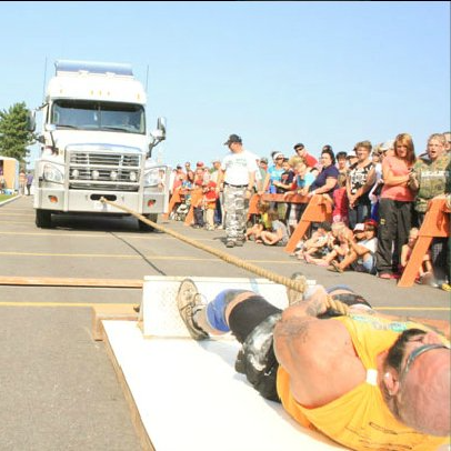 Strongman laying on back pulling a transport truck