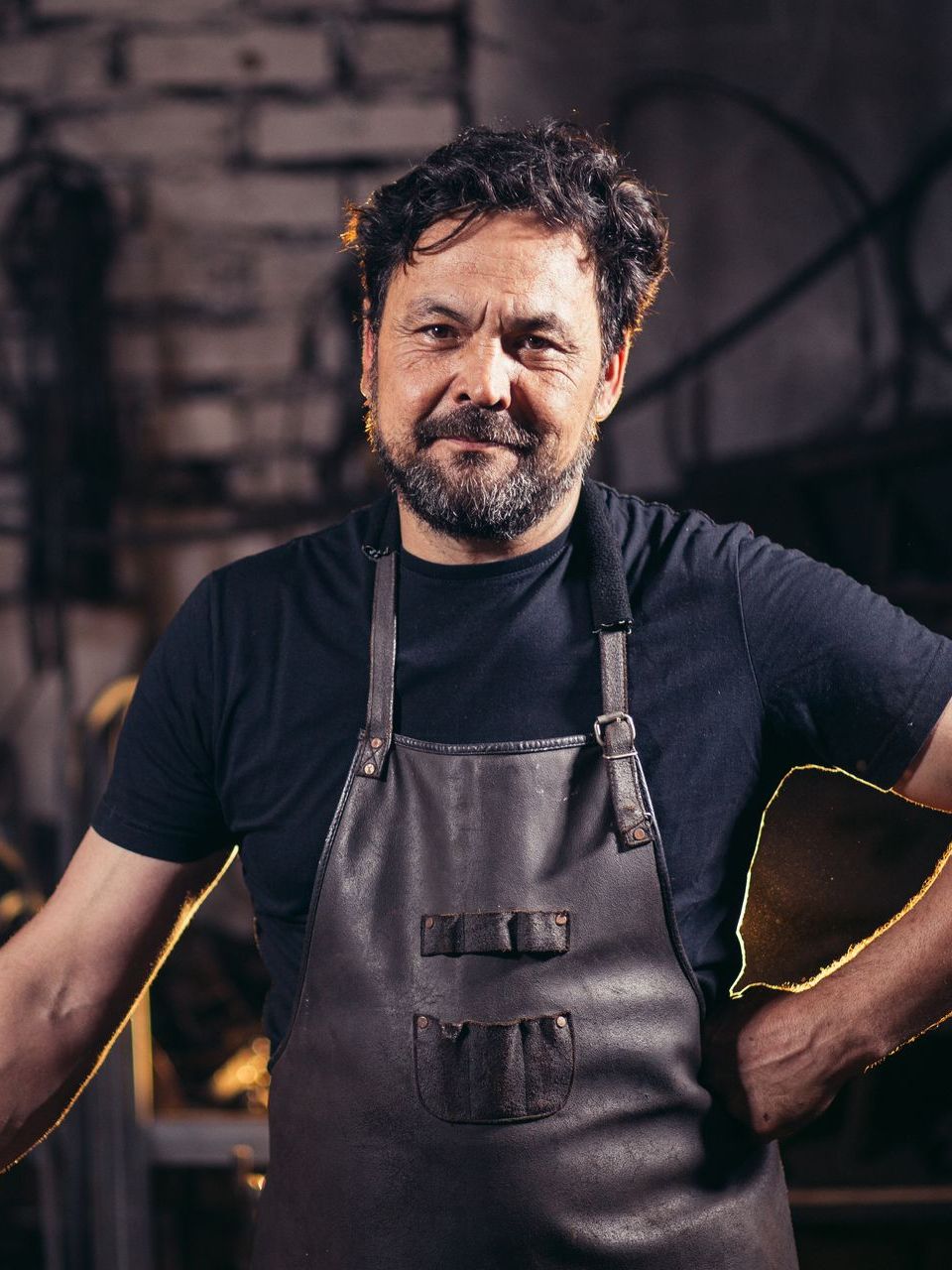 A man with a beard wearing an apron and a black shirt