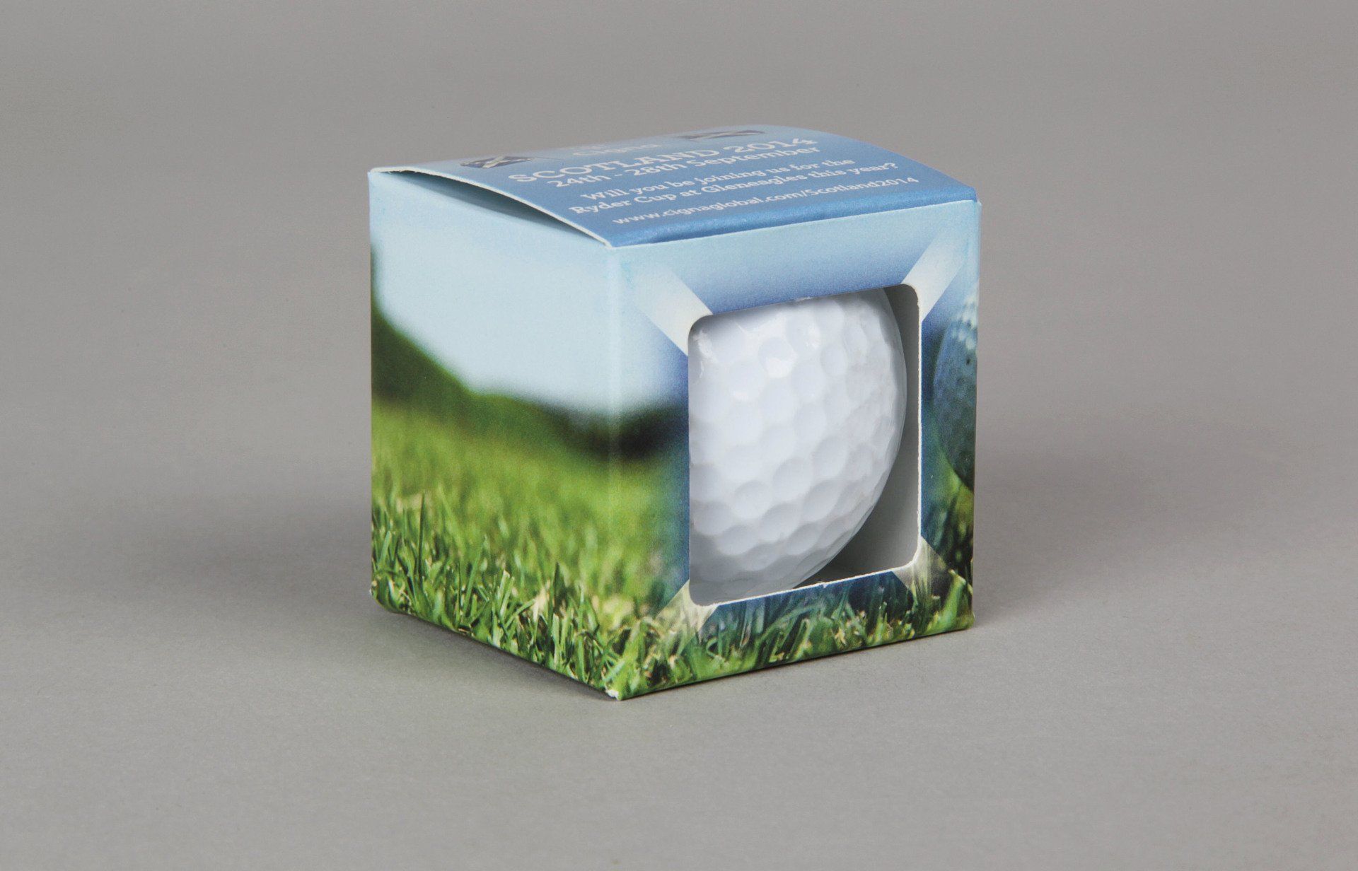 A golf ball in a box with a picture of a golf course on it.