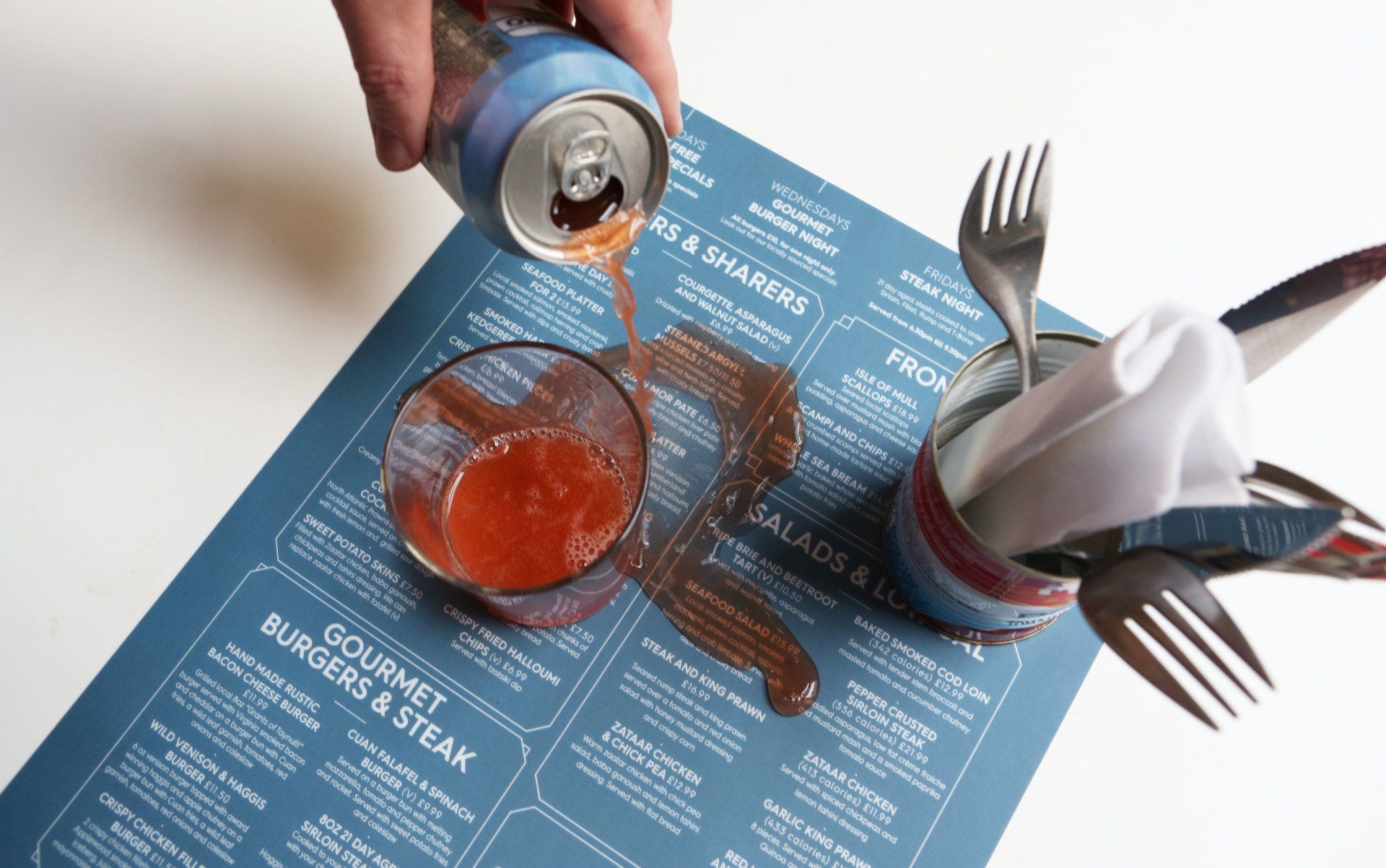 A person pouring a drink into a glass on a menu that says gourmet burgers & steak