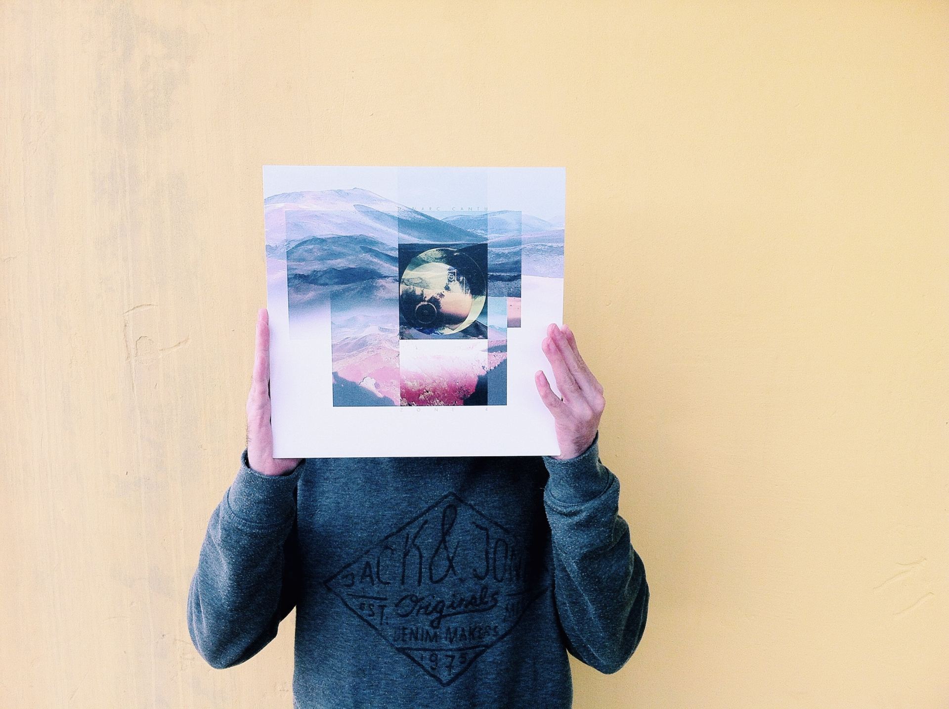 Man holding LP sized artwork in front of his face.
