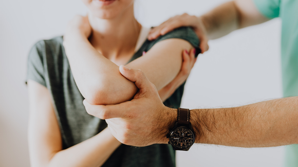 A person's elbow is being examined by another person.