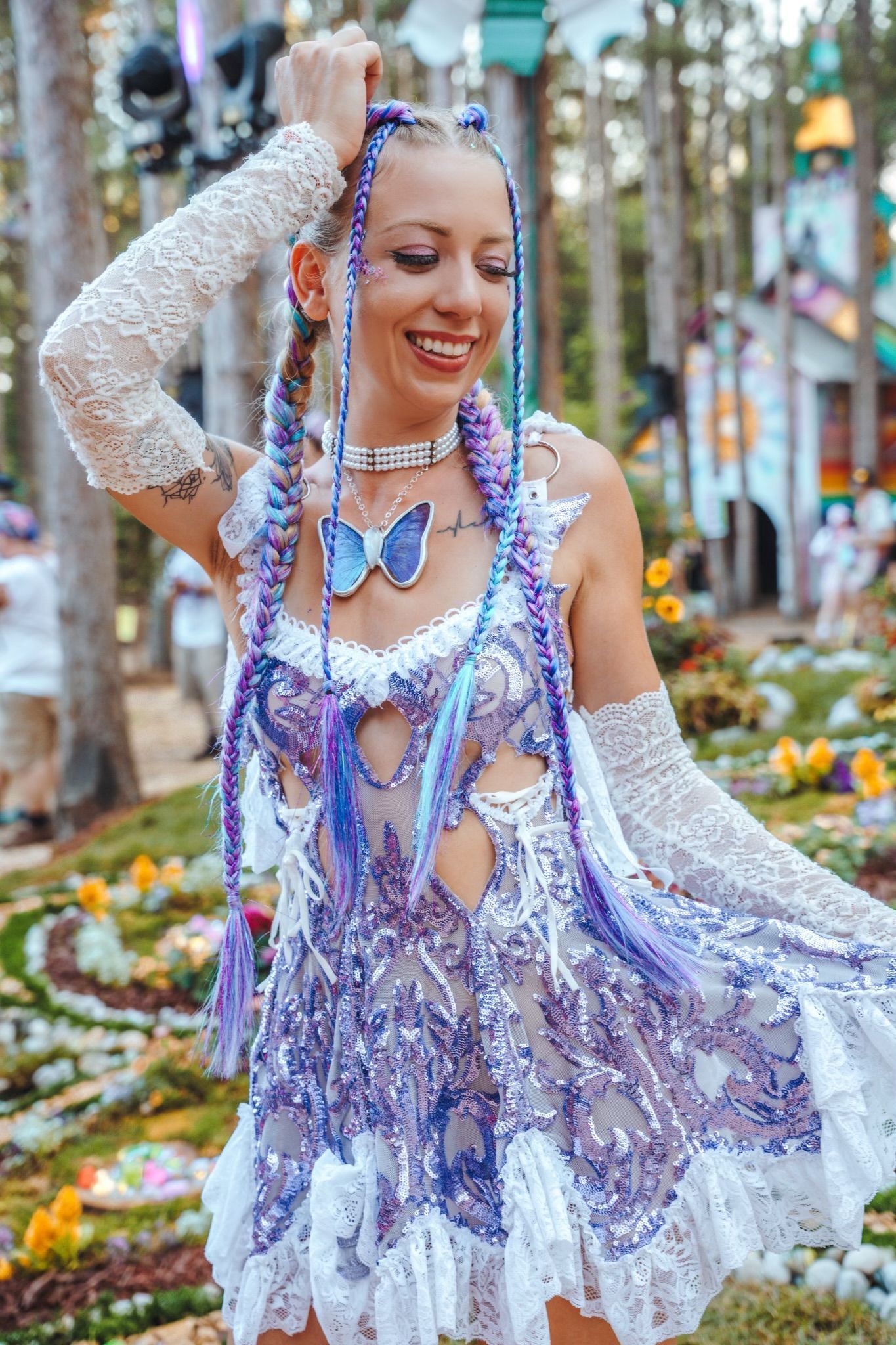 A woman in a purple and white dress is standing in a field of flowers.
